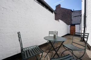 a patio with a table and chairs and a brick wall at Earp House - Allerton Liverpool Stay - Sleeps 7 in Liverpool