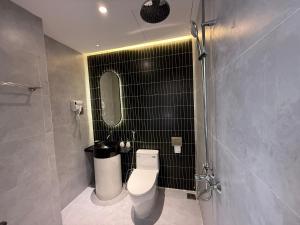 a bathroom with a toilet and a black tiled wall at Palm Hotel in Tam Kỳ