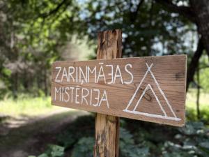 a sign that reads zambias micronesia on a wooden pole at Zariņmājas Mistērija in Ceļarāji