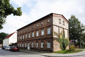 a brick building with cars parked in front of it at Fabrik Gästehaus in Neustrelitz