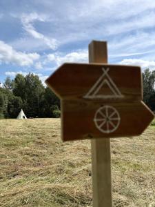 a wooden sign on a pole in a field at Zariņmājas Mistērija in Ceļarāji