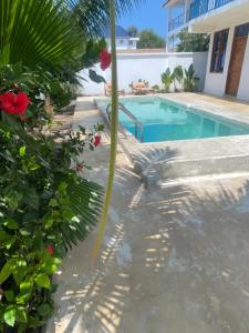 ein Pool mit einer Palme neben einem Haus in der Unterkunft Sabali Lodge, Zanzibar in Jambiani