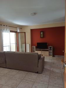 a living room with a couch and a flat screen tv at LA.KI House in Kavála