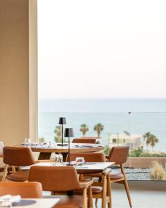 a dining room with tables and chairs and a large window at Este Elegant Suites & Villas - Adults Only in Kiotari