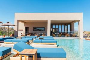 a resort pool with blue lounge chairs and tables at Este Elegant Suites & Villas - Adults Only in Kiotari +103 photos