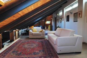 un soggiorno con 2 sedie bianche e un tappeto di Mansarda Zancle a Messina