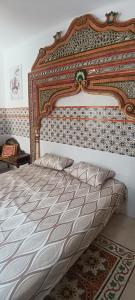 a bed with an ornate headboard in a bedroom at Dar HJAIJA in Hammamet