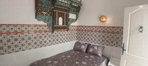 a small room with a bed and a tiled wall at Dar HJAIJA in Hammamet