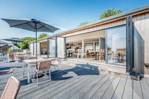 an outdoor deck with tables and chairs and an umbrella at Lodge 66 at Riviera Bay Coastal Retreat in Brixham