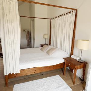 a bedroom with a canopy bed with a table and a lamp at De Watermolen in Ninove