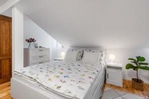 a white bedroom with a white bed with flowers on it at Apartmán TICHO - Ostrůvek in Lesná