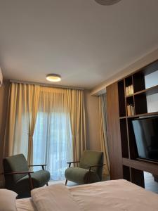 a hotel room with a bed and two chairs and a television at Nordic Nest Kolašin in Kolašin