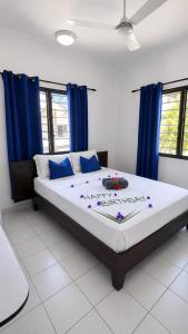 a bedroom with a large bed with blue curtains at Roche Kerlan Apartments in Anse Kerlan