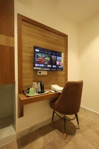 a room with a desk with a chair and a television at Yu Hotel in Kānpur