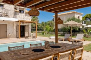 an outdoor dining area with a table and chairs and a pool at Casa Falco in Vasilikos
