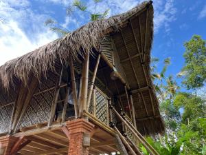 a straw roofed building with a blue sky in the background at Rafka Bamboo Valley in Seribatu