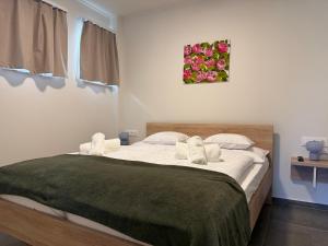 a bedroom with a large bed with a green blanket at Oliva Apartman in Bük