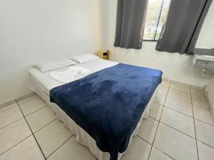 a bedroom with a bed with a blue blanket on it at Hotel Palace Huesca in Presidente Prudente