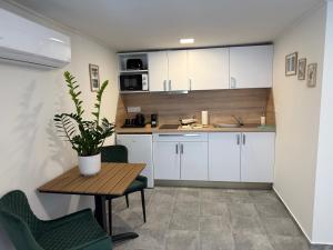 a kitchen with white cabinets and a table with a potted plant at Oliva Apartman in Bük