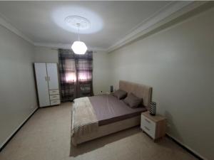 a bedroom with a bed and a lamp in it at Appart Hana in Bab Ezzouar