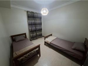 a bedroom with two beds and a window and a chandelier at Appart Hana in Bab Ezzouar