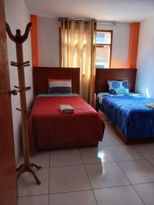 a bedroom with two beds with blue and red sheets at La Posada del Inca Chavin in Chavín de Huantar