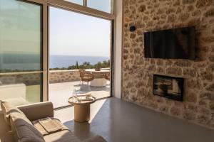 a living room with a fireplace and a view of the ocean at Eks Mani Peninsula Retreat in Pirgos