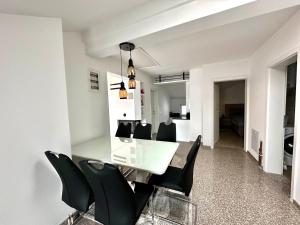 a dining room with a white table and black chairs at Modern Penthouse with Unbeatable Panoramic Views in Peje