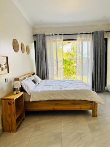 ein Schlafzimmer mit einem großen Bett und einem Fenster in der Unterkunft Bougainvillea House in Mwaja