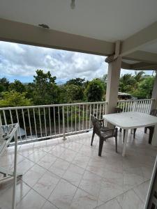 a porch with a white table and chairs on a balcony at Tropical Orange House in Ducos