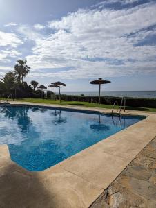 a swimming pool with umbrellas and the ocean at Romantische Auszeit Penthouse mit Meerblick in Sitio de Calahonda