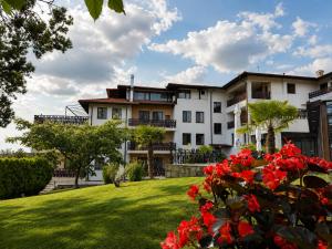 a large white building with red flowers in a yard at Park Hotel Arbanassi in Arbanasi