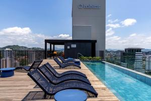 a deck with lounge chairs and a swimming pool on a building at Edificio ON in Blumenau