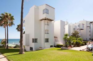 a white building with palm trees and the ocean at Romantische Auszeit Penthouse mit Meerblick in Sitio de Calahonda