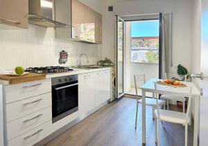 a kitchen with white cabinets and a table with a bowl of fruit at Holihome - LUNA in Tortoreto Lido