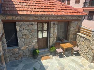 a stone building with a wooden door and a table at Nevoliani stone house in Florina