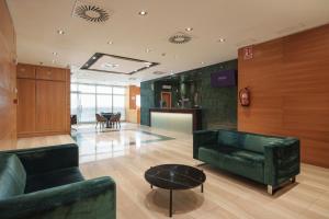 a lobby with two green couches and a table at Dorma León in León