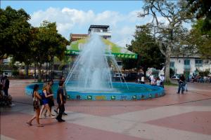 una fuente en una plaza con gente caminando alrededor de ella en Nomada Hostel, en Guatapé