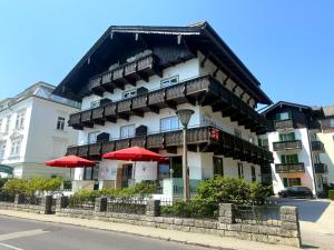 a building with red umbrellas in front of it at Hotel Seerose Wolfgangsee in St. Wolfgang +29 photos