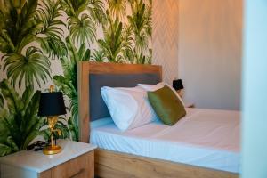 a bedroom with a bed with white sheets and green pillows at N'Log N'Skuraj Hotel in Ferr -Skuraj