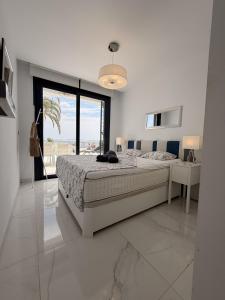a white bedroom with a bed and a large window at Infinity View apartment in Arenales del Sol +47 photos