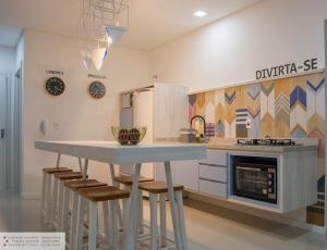 a kitchen with a table and stools in a room at Apartamento Geomundi proximo do lago e Shopping in Toledo
