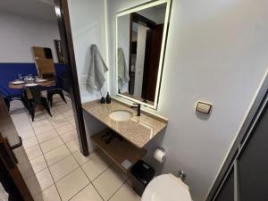 a bathroom with a sink and a mirror and a table at Studio UNI 15 - Unipar, Lago e Shopping in Toledo