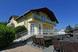 a yellow building with benches in front of it at Royal Villa in Balatonfüred