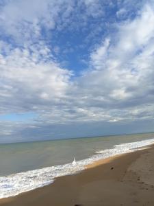 a beach with a cloudy sky and the ocean at Pousada Aquarela de Itaunas in Conceição da Barra