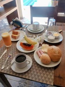 a table with plates of food and a cup of coffee at Pousada Aquarela de Itaunas in Conceição da Barra