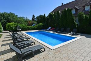 a swimming pool with lounge chairs next to a house at Royal Villa in Balatonfüred