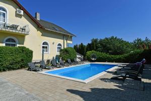 a swimming pool with chairs and a house at Royal Villa in Balatonfüred