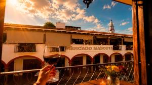 eine Person mit einem Glas Wein auf einem Balkon in der Unterkunft Copa de Oro Hotel Boutique in Mascota