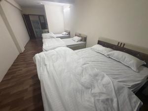 three beds in a room with white sheets at Double tree 2 in Burhānilkantha